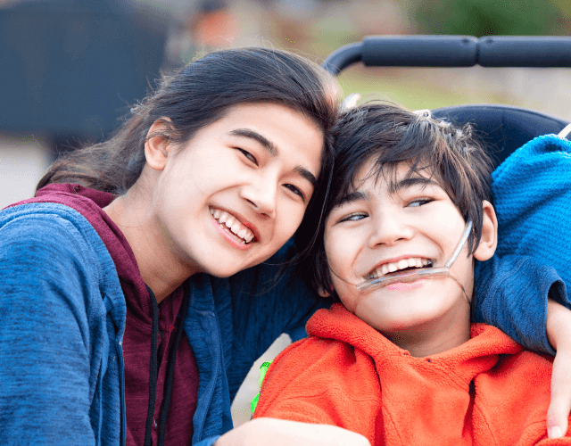 Image of a young disabled boy smiling with sister