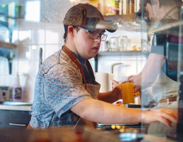 Image of young man serving orange juice in a restaurant